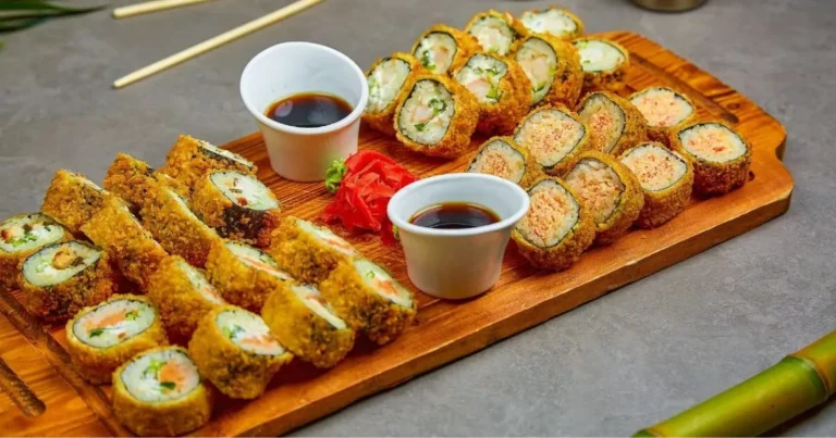 Freshly made salmon sushi rolls on a bamboo plate with dipping sauce and wasabi